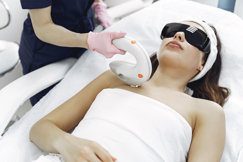 a woman at laser treatment,lying on the bed wearing glasses to be protect her eyes from laser light