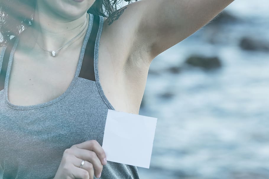 a woman is holding up a strip for her underarm hair removal