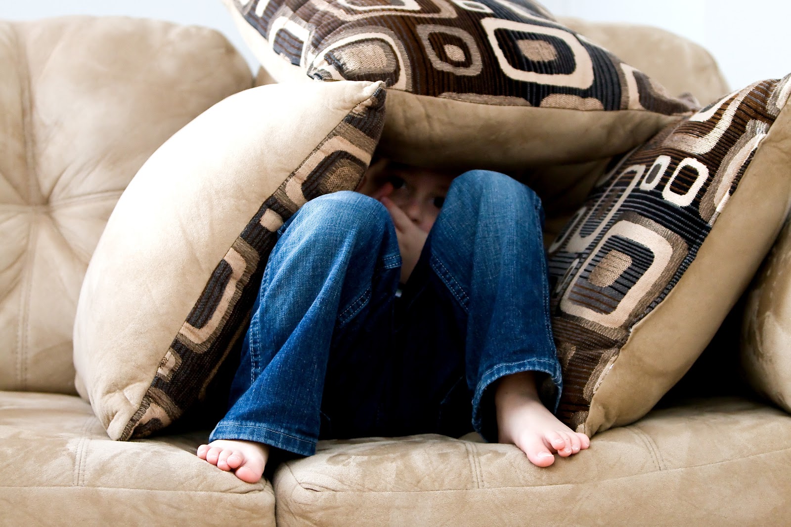 a child is covering himself with cushions