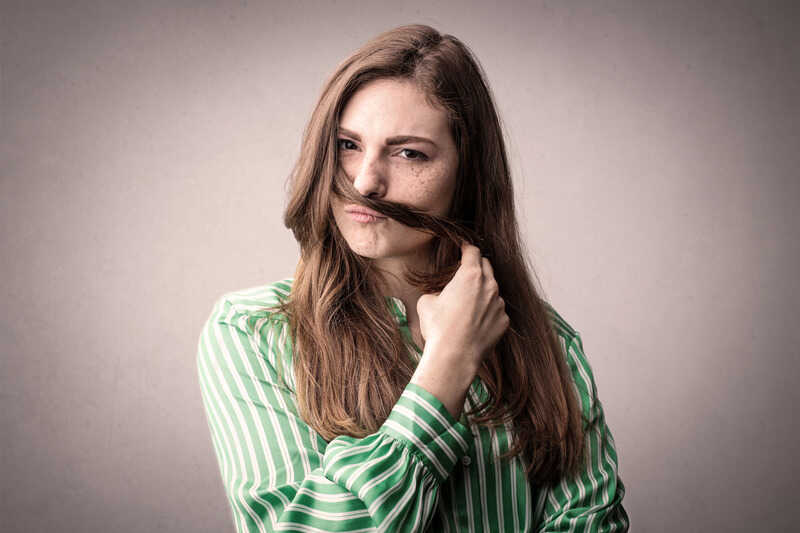 a woman closing her nose with her hair to avoid offensive odor