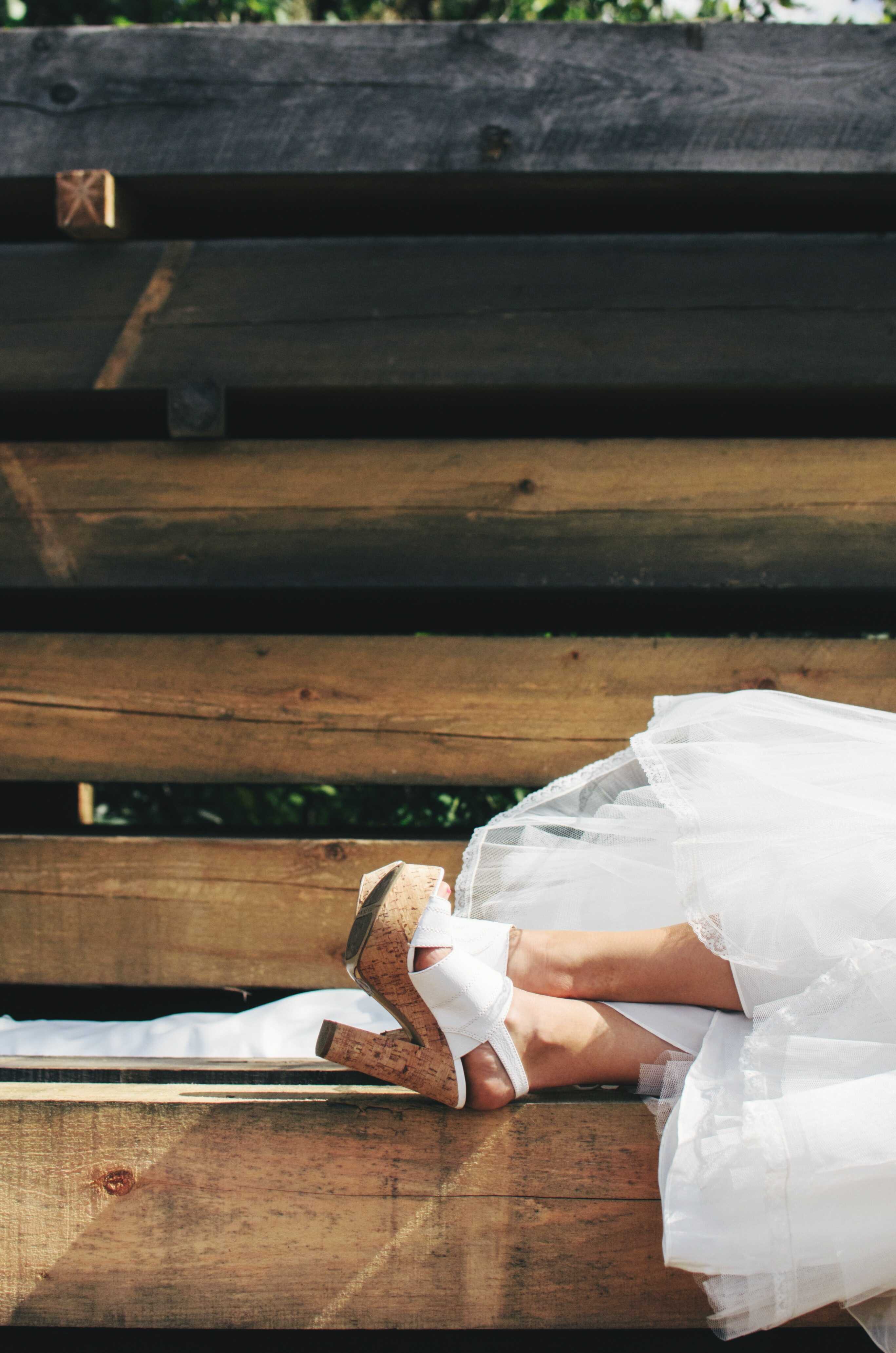 a woman sitting on the chair wearing a white dress and a white sandal