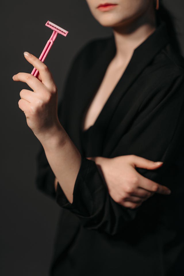 Person in Black Long Sleeves Holding a Pink Razor